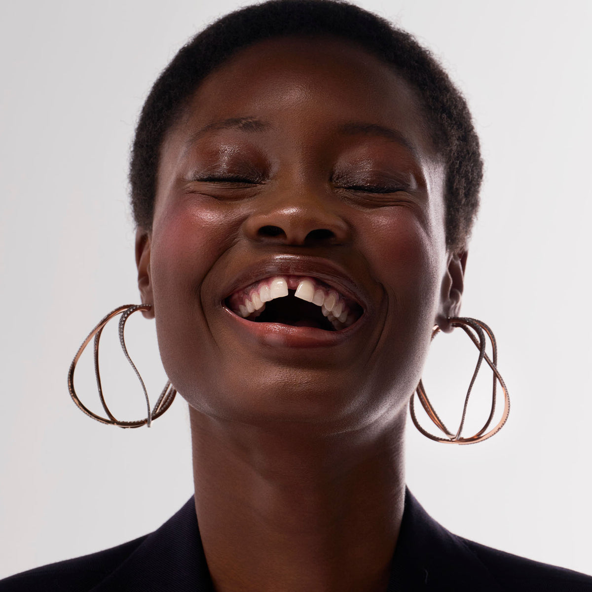 A young woman is wearing three transformable jewels : three bangle-hoop earrings. The fine jewelry pieces are crafted in 18k gold and set with natural diamonds. The set represent the caustic light which is the inspiration of the collection, blending the MARIE MAS two main sources of inspiration: water and light.